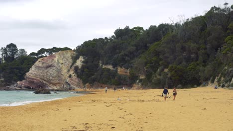 People-Walking-Along-Sandy-Beach-In-Eden-Australia,-Ocean-Shore-Landscape