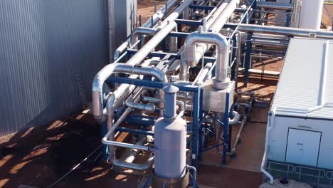 Drone-shot-looking-down-on-metal-pipes-and-infrastructure-at-an-industrial-facility