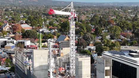 Drone-shot-moving-towards-a-construction-site-with-a-white-crane