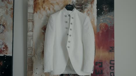 White-embroidered-suit-hanging-on-a-hanger,-highlighting-elegant-wedding-attire