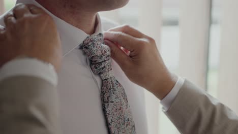 Primer-Plano-Del-Novio-Ajustando-Su-Corbata-Floral,-Capturando-Un-Momento-De-Preparación-Y-Elegancia