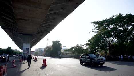 Pan-shot-of-the-street-is-crowded-with-people,-vehicles,-and-shops-on-the-side-revealing-Coimbatore-International-Airport-Board