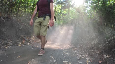 A-couple-hiking-on-a-dusty-trail-in-a-sunlit-forest-at-Mount-Batur,-Bali,-Indonesia