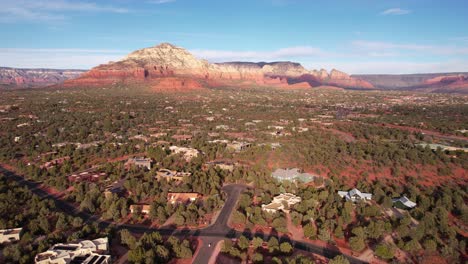 Aerial-View-of-Breathtaking-Landscape-Around-Sedona,-Arizona-USA,-Homes-in-Valley-Under-Red-Sandstone-Hills