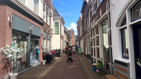 Pov-walk-on-modern-street-of-small-dutch-town-during-sunny-summer-day