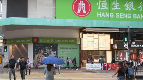 Se-Ven-Peatones-Cruzando-La-Calle-Frente-A-La-Sucursal-Del-Banco-Hang-Seng-En-Hong-Kong