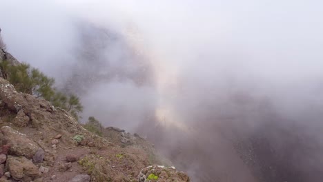 A-view-of-misty-clouds-spilling-into-the-crater-of-Mount-Vesuvius-in-Naples,-Italy---Panning-shot