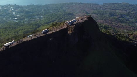 Aerial-truck-drone-shot-around-a-mountain-hill,-sightseeing-Indonesia,-green-trees-in-background,-copy-space-and-slow-motion-by-daylight