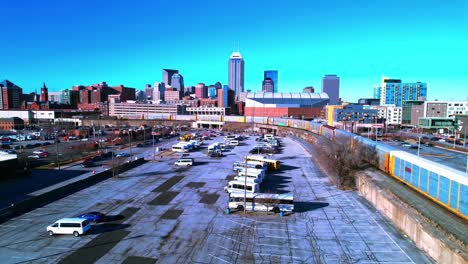 Drone-flight-over-a-train-driving-through-downtown-of-Indianapolis-city-on-a-sunny-day,-strong-colorful,-slow-motion-and-copy-space