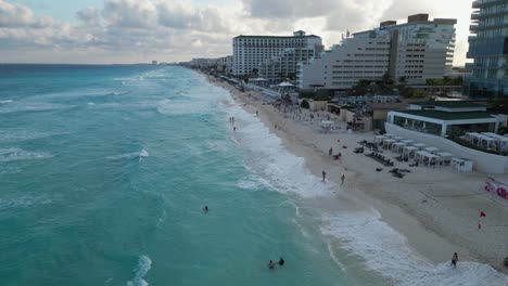 Low-Caribbean-beach-aerial-flyover,-resort-hotels-in-Cancun,-Mexico