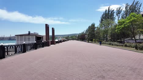 A-view-down-an-empty-promenade,-Crimea,-with-the-sea-in-the-background-and-a-small-building-to-the-left