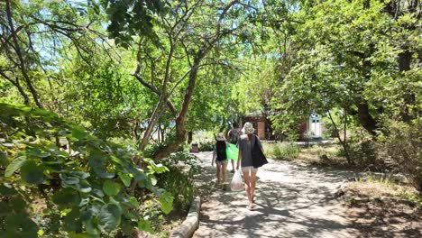 Three-people-walk-along-a-path-through-a-forested-area-in-Karadag,-Crimea