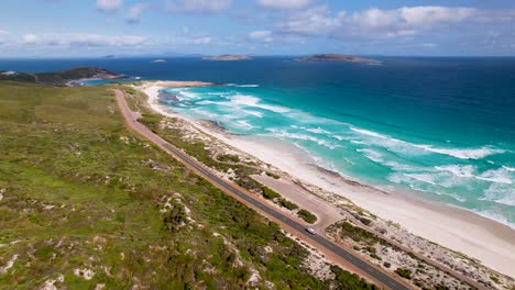 4K-drone-video-of-a-camper-van-driving-along-a-stunning-long-road-next-to-a-beautiful-beach-in-Esperance,-Western-Australia