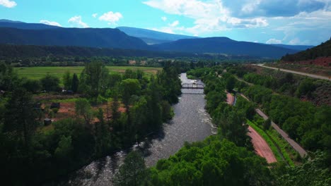 Carbondale-Roaring-Fork-River-Glennwood-Springs-Marble-Basalt-Aspen-Snowmass-summer-aerial-drone-Colorado-June-July-Rocky-Mountain-snow-cap-peaks-Marble-El-Jebel-clouds-sunny-forward-pan-up-motion