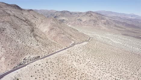 Drone-flying-sideways-following-a-car-driving-on-a-desert-road-in-4k