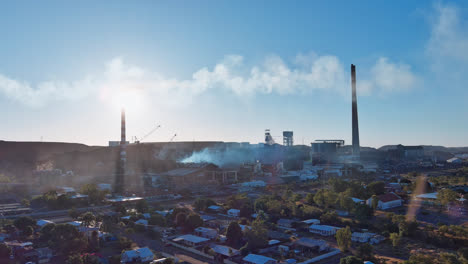 Track-left,-Plumes-of-smoke-and-steam-coming-from-the-chimneys-at-the-Mount-Isa-mines-with-blue-sky-and-houses-and-buildings-in-the-foreground