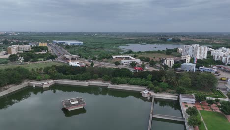 Luftaufnahmen-Eines-Ruhigen-Sees-Neben-Der-Autobahn,-Mit-Fahrzeugen,-Die-Am-Wasserrand-Entlangfahren-Und-Eine-Ruhige-Und-Malerische-Szenerie-Schaffen