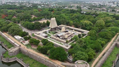 Aerial-Shot-of-Vellore-Temple-surrounded-by-Thick-Forest-near-a-pond