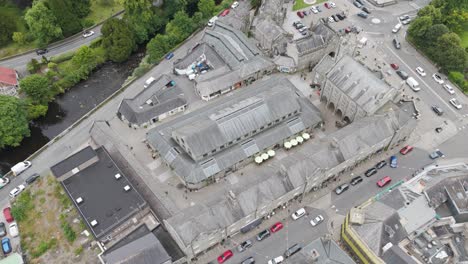 Aerial-view-of-central-Tavistock-highlighting-the-bustling-Pannier-Market-surrounded-by-historic-buildings,-Tavistock,-Devon,-UK