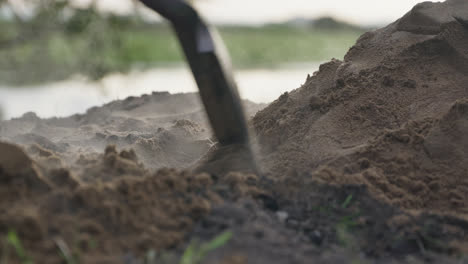 Close-up,-slow-motion,-A-shovel-is-raking-steaming-hot-dirt-from-a-pile-over-an-underground-cooking-pit-in-the-outback