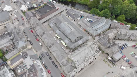 Drone-view-of-the-Pannier-Market-in-Tavistock-surrounded-by-historic-architecture-and-busy-streets,-Tavistock,-Devon,-UK