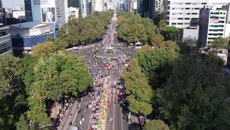 Drone-shot-of-Day-of-the-Dead-parade-mass-gathering-of-people-on-Huntress-Diana-Fountain-roundabout-intersection-leads-to-Angel-of-Independence-historical-monument-in-Mexico-City