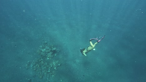 Woman-freediving-in-clear-blue-water-near-a-coral-reef-in-Tulamben,-Bali