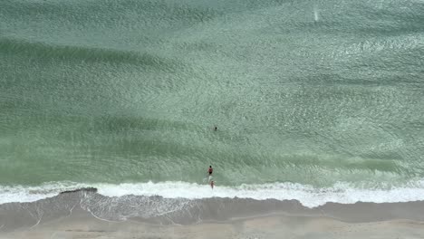 Family-swimming-at-the-shore-of-Myrtle-Beach,-South-Carolina-while-waves-crash-and-it's-raining