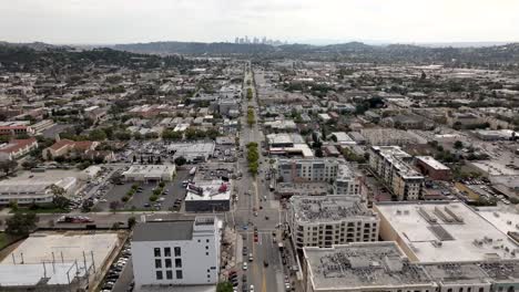 Glendale-neighborhood-below-with-Los-Angeles'-iconic-skyline-on-the-horizon---aerial-flyover