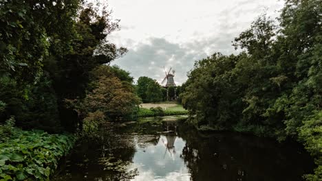 Timelapse-footage-from-a-bridge-in-Bremen,-Germany,-featuring-a-windmill-surrounded-by-lush-greenery