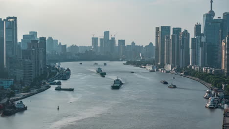 Hermoso-Amanecer-Sobre-Los-Rascacielos-De-La-Ciudad,-Edificio-Emblemático-Rodeado-De-Flujo-De-Barcos-En-El-Distrito-Financiero-A-La-Hora-Del-Amanecer,-Apartamento-Residencial-Cerca-Del-Río-Y-El-Puente