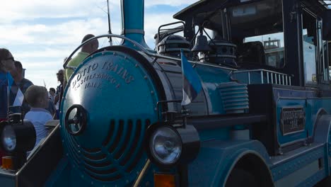 Slowly-moving-footage-of-a-blue-trackless-dotto-train-at-the-harbor-during-festival