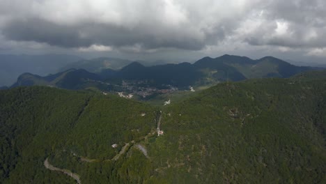 Mexico-green-forest-and-curved-bend-road-in-the-hills,-cloudy-moody-sky