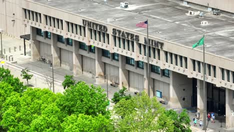 United-States-Mint-in-Philadelphia,-large-building-with-American-flag,-people-near-entrance,-aerial