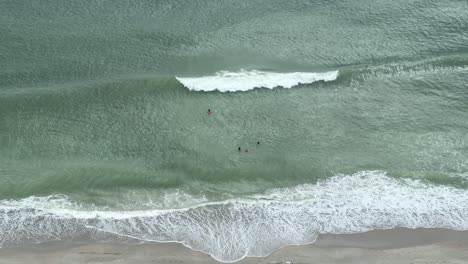 Family-Swims-in-the-Green-Ocean-at-Myrtle-Beach,-South-Carolina-as-a-wave-rolls-into-shore-in-slow-motion