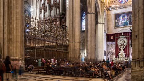 Tourists-exploring-the-grand-interior-of-Seville-Cathedral,-Spain,-featuring-ornate-architecture,-intricate-artwork,-and-historic-elements