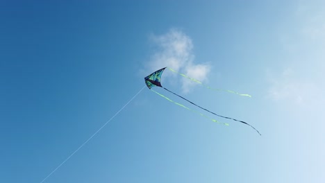 Blue-and-green-kite-with-three-tails-flying-in-a-clear-sky-from-below