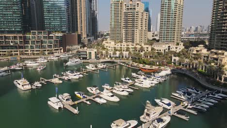 Luftaufnahmen-Der-Dubai-Marina-Mit-Ihrer-Ikonischen-Uferpromenade,-Hohen-Wolkenkratzern-Und-Einer-Ruhigen-Ansammlung-Von-Booten-Und-Yachten