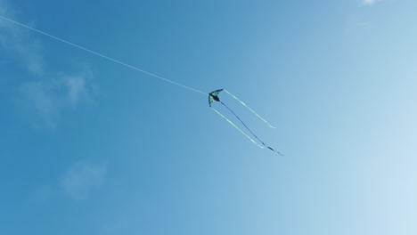 Green-and-blue-kite-flying-with-the-clear-blue-sky-on-the-background