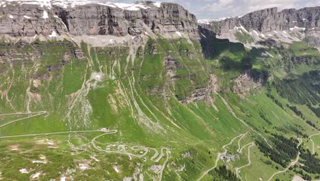 Aerial-view-of-the-majestic-mountain-range-and-landscape-of-Klausenpass,-Urner-Boden,-Schweiz,-featuring-high-cliffs-and-a-valley-intersected-by-roads