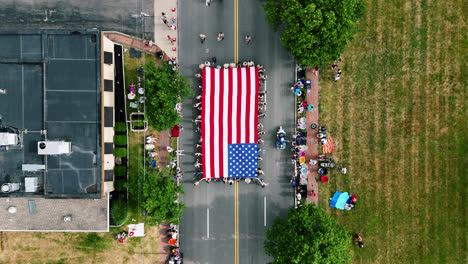 Vertikale-Ansicht-Einer-Riesigen-Amerikanischen-Flagge,-Die-Während-Der-Parade-Zum-4.-Juli-In-Centerville,-Ohio,-Auf-Der-Straße-Getragen-Wird