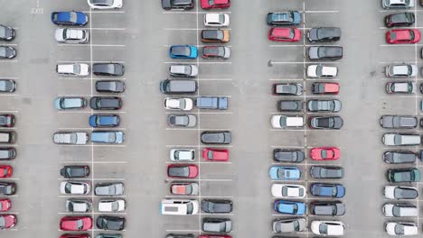 Top-down-flyover-of-a-busy-UK-carpark-with-numerous-parked-cars,-highlighting-the-organized-parking-layout