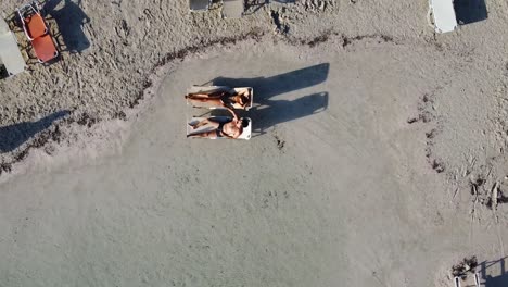 Top-View-of-Young-Romantic-Couple-on-Sun-Loungers-by-the-Sea,-Balos-Beach