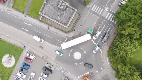 Top-down-aerial-view-of-UK-police-helping-a-broken-down-lorry-stuck-on-the-road,-managing-the-traffic-situation