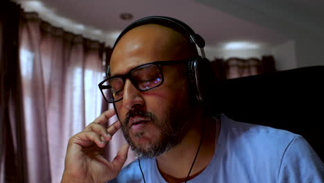 South-asian-man-is-listening-to-music-through-headphones,-enjoying-a-moment-of-relaxation-at-home