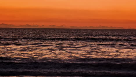 Slow-motion-of-beautiful-scenic-early-morning-sun-rise-rays-over-lake-sea-beach-inlet-water-waves-on-horizon-orange-sky-clouds-in-nature-holidays-outdoors