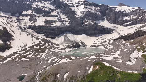 Vista-Aérea-De-Un-Paisaje-Montañoso-Con-El-Lago-Glacial-Gletschersee-En-Su-Base,-Ubicado-En-Klausenpass,-Urner-boden,-Schweiz,-Mostrando-Tanto-Klausenpass-Como-Griesslisee.