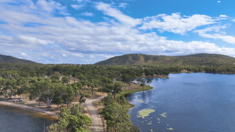 Aerial-tracks-towards-the-narrow-headland-of-Lake-Eungella-revealing-road-tracks-and-a-few-freedom-campers-amidst-the-stunning-trees-and-vistas-of-the-region-in-Queensland