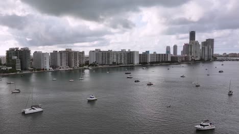 Dunkle-Wolken-über-Der-Innenstadt-Von-Miami-City-Mit-Wolkenkratzern-Und-Vielen-Booten-In-Der-Bucht