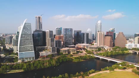 Stunning-reverse-zoom-shot-4K-aerial-view-of-downtown-Austin,-TX,-featuring-skyscrapers,-Lady-Bird-Lake,-Congress-Bridge,-and-Zilker-Park-on-a-sunny-day